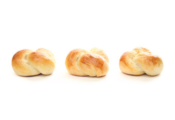 Isolated bread buns arranged in a row. Three baked bread knot roll with egg wash. Traditional Swiss butter bread called Zopf or Challah prepared for holiday meals. White background