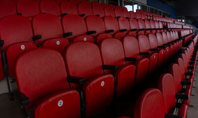 Obraz premium Numbered red stadium seats with angled perspective toward pitch. Shot with anamorphic lens.