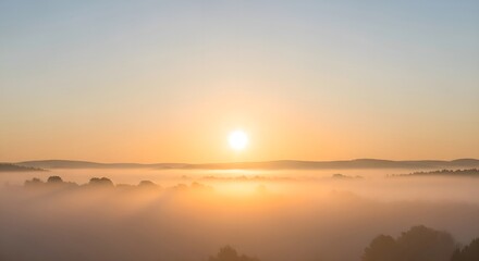 A tranquil morning scene as the sun ascends over a sea of fog, illuminating the misty valley below