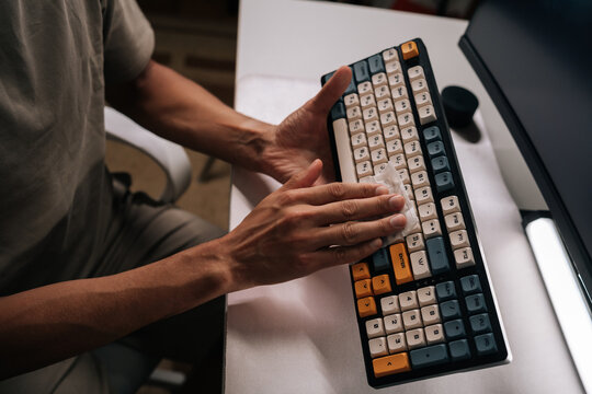 Closeup of person cleaning computer keyboard with disposable wipe, maintaining hygiene, ensuring germ-free surfaces, performing regular maintenance on office equipment to keep functional and clean. - Powered by Adobe