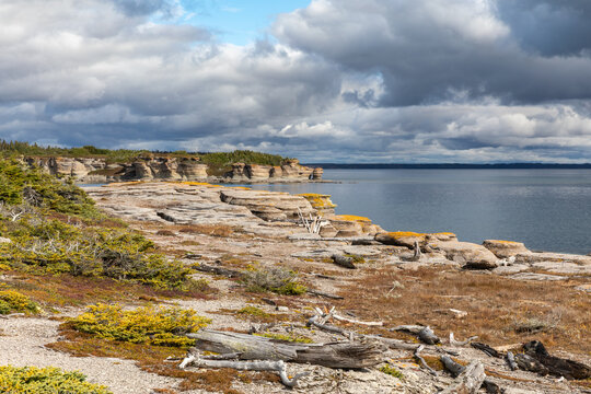 Colorful Limestone Cliffs and Rocky Shoreline of Petite Ile au Marteau Island near Havre Saint Pierre, Quebec, Canada on a Cloudy Autumn Day