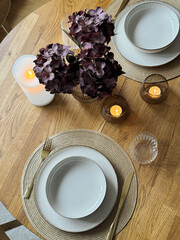 Wooden round table setting with glassware and vase creating a stylish evening atmosphere