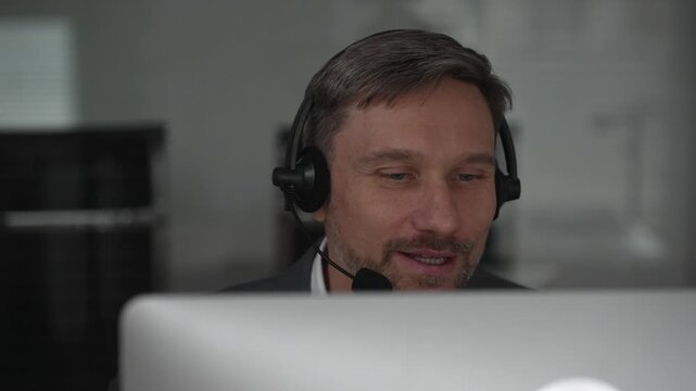 Male customer service representative providing assistance and communicating with clients, offering online support using virtual communication tools in a modern workspace. Business concept