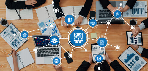 A diverse team engaged in strategic planning and data analysis, utilizing modern technology and visual tools for effective communication and collaboration. Amity