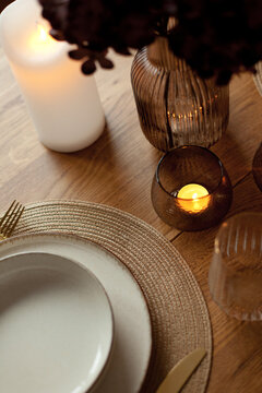 Wooden round table setting with glassware and vase creating a stylish evening atmosphere