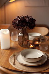 Wooden round table setting with glassware and vase creating a stylish evening atmosphere