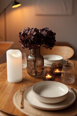 Wooden round table setting with glassware and vase creating a stylish evening atmosphere