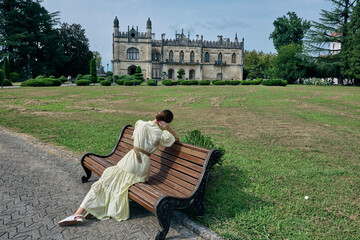 Fototapeta premium woman on bench in park near historic manor, authentic inclusive