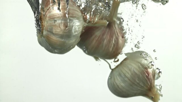 The heads of fresh garlic fall under the water. Filmed on a high-speed camera at 1000 fps. High quality FullHD footage