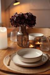 Wooden round table setting with glassware and vase creating a stylish evening atmosphere