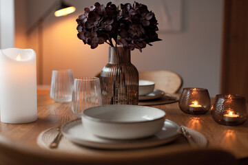 Wooden round table setting with glassware and vase creating a stylish evening atmosphere