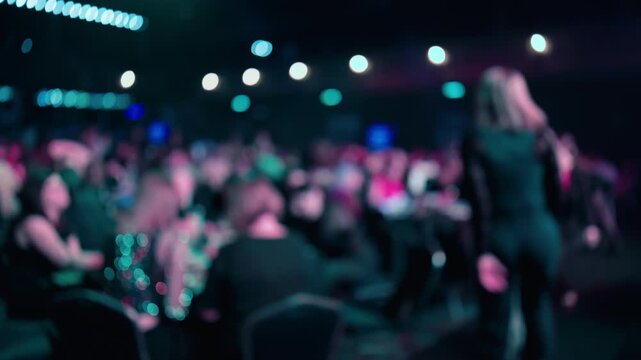 Audience cheers loudly, Attendees in auditorium enthusiastically cheer and show celebration energy