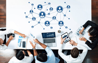 A diverse group of professionals collaborating in a modern office setting, analyzing data and graphs while utilizing technology to enhance networking and communication efforts. Amity