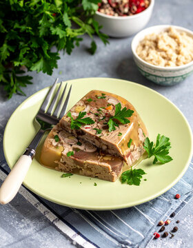A plate of Ukrainian holodets aspic is garnished with parsley and served with spicy horseradish.