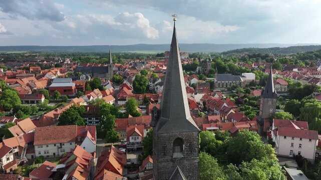 Slow drone orbit around a church spire with several nearby churches and Castle Hill on the horizon in Quedlinburg, Saxony-Anhalt, Harz region.
