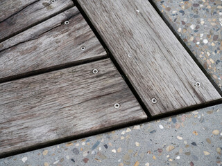 Fototapeta premium Diagonal view of weathered wooden planks with screws on terrazzo flooring showing texture contrast.