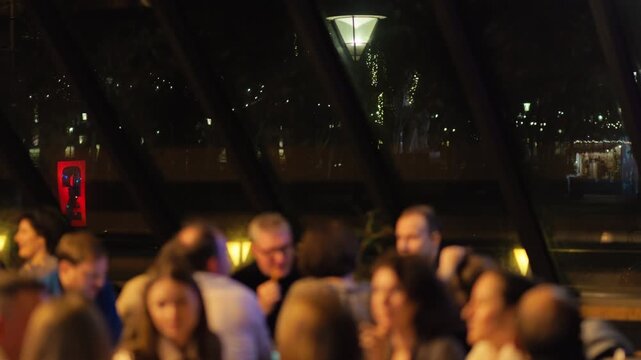 Guests dine with city view, Evening feast by window overlooking vibrant city lights with friends
