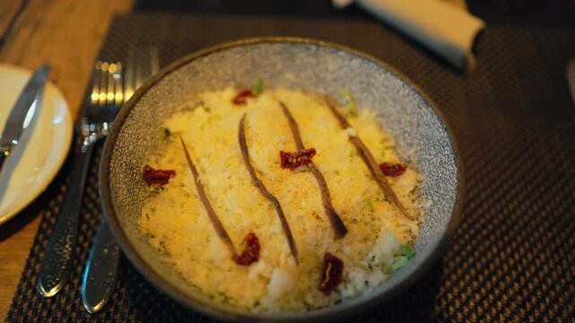 Sophisticated rice risotto setup featuring sundried tomato accents and warm mood lighting for video capture