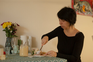 caucasian woman spreading jam on toast at table, jars and flowers nearby, morning sunlight, calm breakfast ritual with knife and plate, relaxed domestic scene emphasizing nourishment and cozy routine