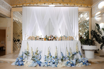 Elegant wedding reception setup with blue floral arrangement and draped backdrop