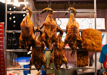 Whole roasted duck cooking on a spit over a smoky coal fire for a delicious outdoor barbecue dinner