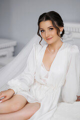 Naklejka premium Portrait of a bride in a white dress sitting on a bed with elegant decor