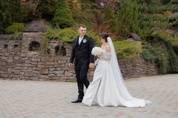 Wedding couple walking hand in hand in a garden setting on a beautiful autumn day