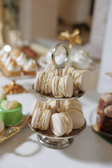 Elegant display of white macarons on a tiered stand at a festive dessert table