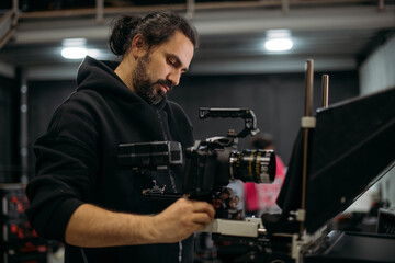The director of photography with a camera on the set. A professional videographer is working on filming a movie or commercial for a TV series. The filming process takes place indoors in a studio.
