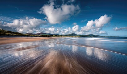 Expansive beach under a cloudy sky with dramatic reflections on wet sand