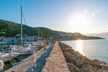 Scenic coastal sunset with yachts docked in mediterranean bay. Baška, Krk island, Croatia