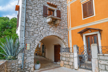 Fototapeta premium Charming mediterranean village alley with stone and orange buildings. Omišalj, Krk island, Croatia