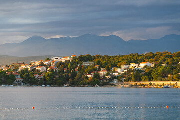 Sunlit coastal village by the sea with mountain backdrop in croatia. Omi&scaron;alj, Krk island, Croatia