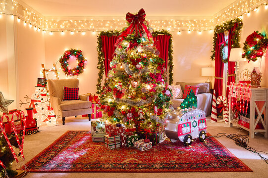 Festive living room decorated with illuminated Christmas tree, wreaths, string lights, and holiday ornaments