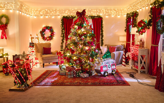Festive living room decorated with Christmas tree, string lights, wreaths, and red holiday accents