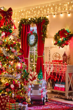 Festive living room decorated with Christmas tree, garland, string lights, and red holiday accents