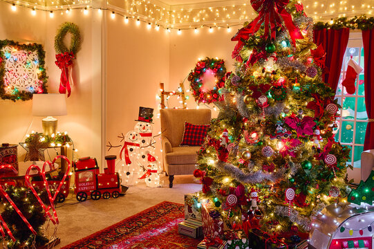 Festive living room decorated with illuminated Christmas tree, wreaths, string lights and holiday ornaments