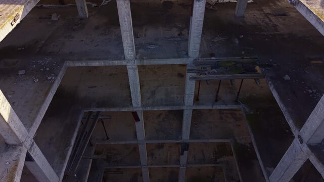Sunlight casts shadows across the hollowed interior of a deserted building, revealing remnants of a forgotten past as nature begins to reclaim the space.