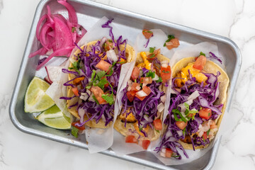 Overhead view of Latino food for a hungry patron includes a trio of beer batter fish tacos