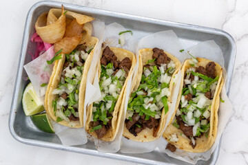 Overhead view of Latino food for a hungry patron includes a trio of carne asada street tacos