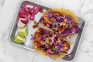 Overhead view of Latino food for a hungry patron includes a pair of grilled fish tacos