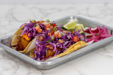 Latino food for a hungry patron includes a pair of grilled fish tacos