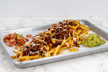 Latino food for a hungry patron includes a huge plate of asade fries loaded with cheese and sour cream