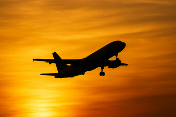 Airplane taking off silhouette against golden sunset sky