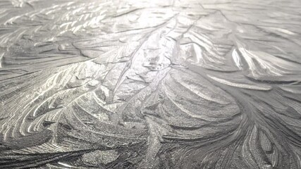 sunlight shining on a frozen surface of ice revealing beautiful pretty floral flowery patterns of  freezing water particles forming crystals.  The camera slowly pulls away and zooms out graduallly - Powered by Adobe