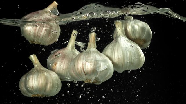 The heads of fresh garlic fall under the water. Filmed on a high-speed camera at 1000 fps. High quality FullHD footage