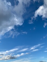 Clear blue sky with soft white and light gray clouds forming a calm, peaceful natural background. Bright daytime atmosphere with gentle cirrus clouds and open space for text or design.