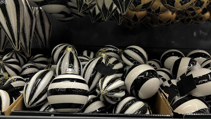 Horizontal mobile photo close up. Stylish glass Christmas tree ball, white bauble with black stripe, toy on mass market, supermarket shelf. Concept of Christmas, New Year, eve, shopping, gift, sale