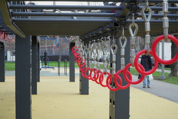  modern urban ninja warrior obstacle course with hanging rings climbing nets monkey bars and rope obstacles on soft rubber surface in public park with people training © GorelovIlya