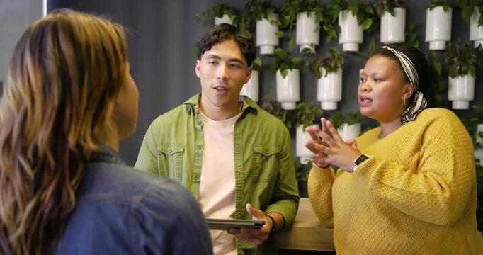 Diverse coworkers questioning presenter explaining tablet and interpreter signing at office nook